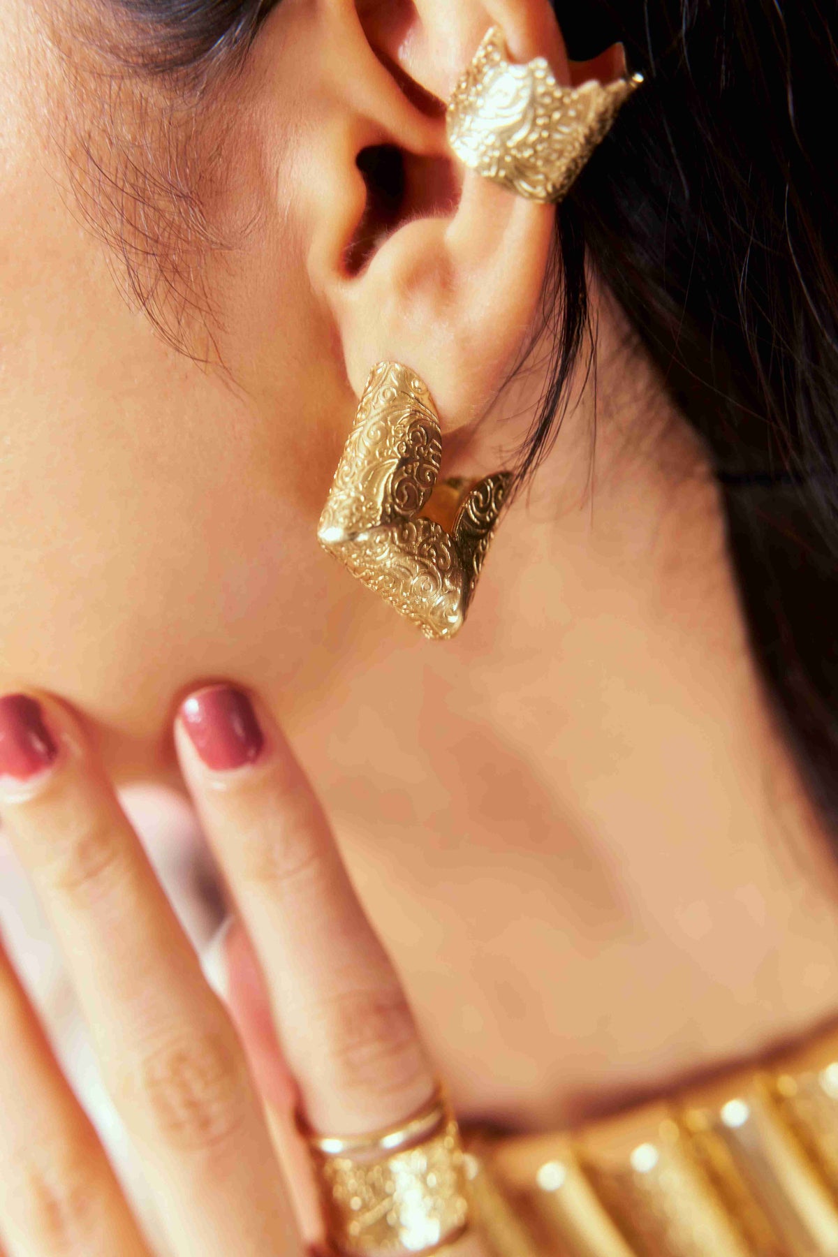 Close-up of a woman wearing gold hoop earrings with a blurred background