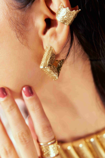 Close-up of a woman wearing gold hoop earrings with a blurred background