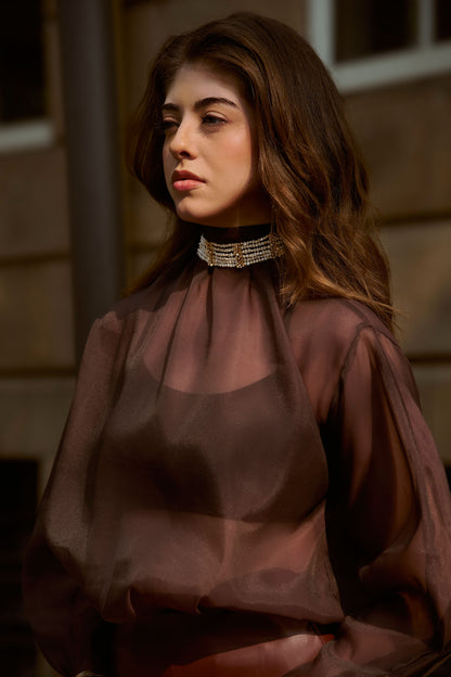 Woman in a sheer brown blouse styled with the Scarlet multi-strand pearl choker necklace in gold plated brass